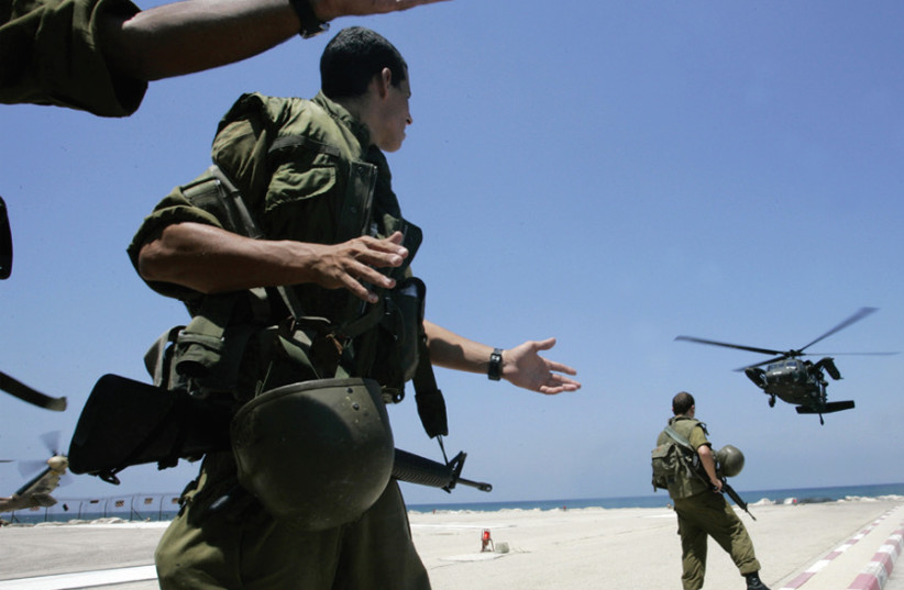 IDF soldiers watch as a helicopter carrying wounded soldiers lands at a hospital in Haifa, on July 26, 2006. (photo credit: ELIANA APONTE/REUTERS)