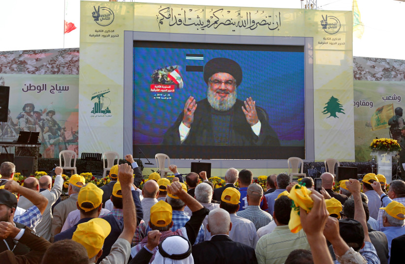 Lebanon's Hezbollah leader Sayyed Hassan Nasrallah gestures as he addresses his supporters via a screen during a rally marking the anniversary of the defeat of militants near the Lebanese-Syrian border, in al-Ain village, Lebanon August 25, 2019.  (photo credit: REUTERS)