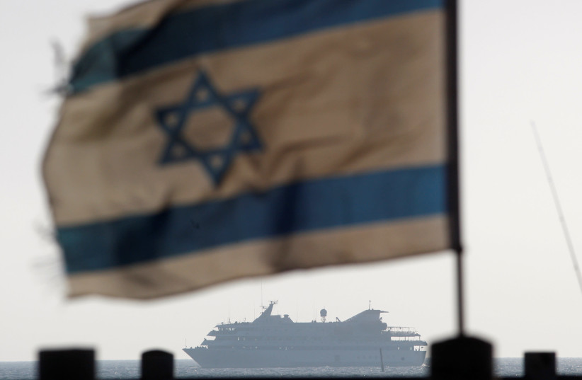 An Israeli flag flutters in the wind as a naval vessel (not seen) escorts the Mavi Marmara, a Gaza-bound ship that was raided by Israeli marines, to the Ashdod port May 31, 2010 (credit: AMIR COHEN/REUTERS)