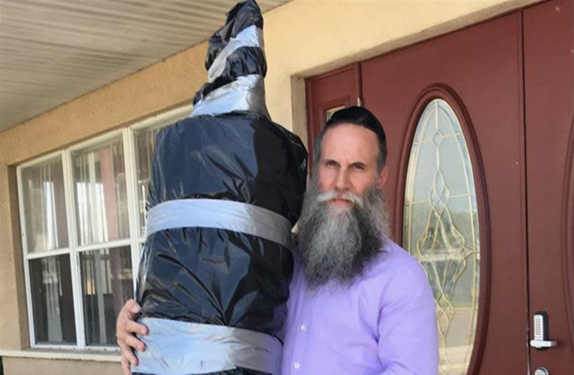 Rabbi Zvi Konikov with one of three Torah scrolls being transported off Satellite Beach, the barrier beach where Chabad of the Space & Treasure Coasts is located, and onto the Florida mainland for safekeeping. (photo credit: CHABAD)