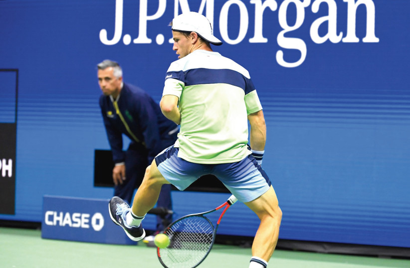 Diego Schwartzman (and inset) hits a return between his legs during his fourth-round four-set victory over Alexander Zverev late Monday night at the US Open.  (photo credit: REUTERS)