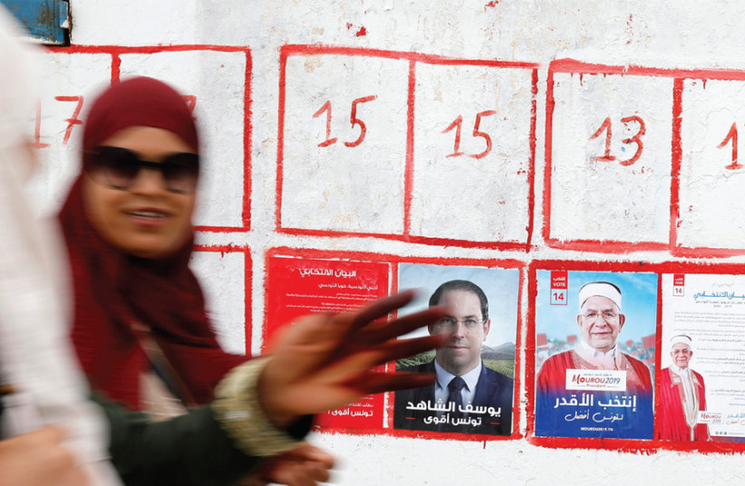 WOMEN WALK past election posters of presidential candidates in Tunis this week. (photo credit: ZOUBEIR SOUISSI / REUTERS)