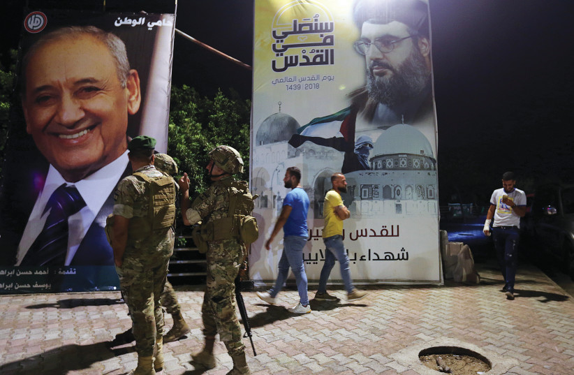 Lebanese army soldiers near a Hezbollah poster  (photo credit: REUTERS)