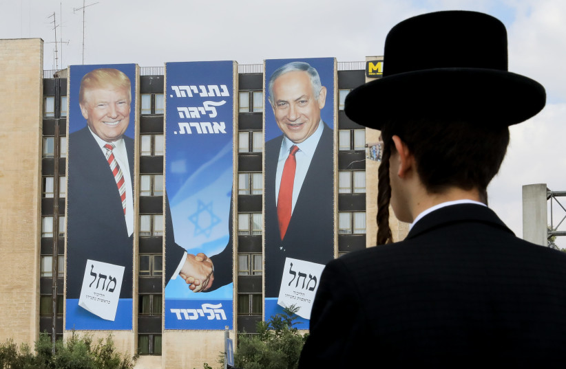 A haredi man stares at a Likud ad with Prime Minister Benjamin Netanyahu and US President Donald Trump. (photo credit: MARC ISRAEL SELLEM)