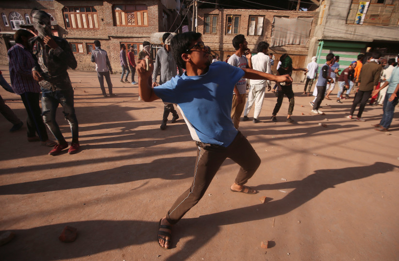 A Kashmiri boy throws a stone towards Indian security forces (not pictured) during clashes, after scrapping of the special constitutional status for Kashmir by the Indian government, in Srinagar, September 6, 2019 (photo credit: REUTERS)