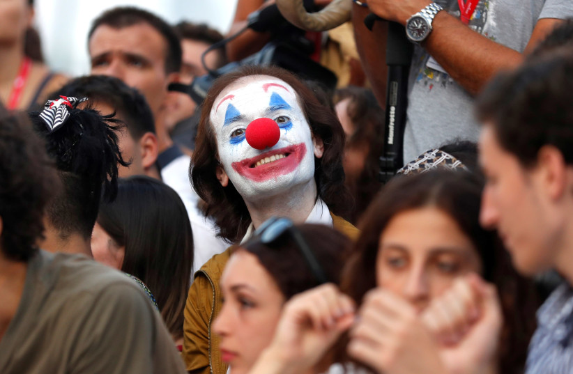 The 76th Venice Film Festival - Screening of the film "Joker" in competition - Red Carpet Arrivals- Venice, Italy, August 31, 2019 - A fan dressed as the Joker poses for a photo. (photo credit: YARA NARDI / REUTERS)