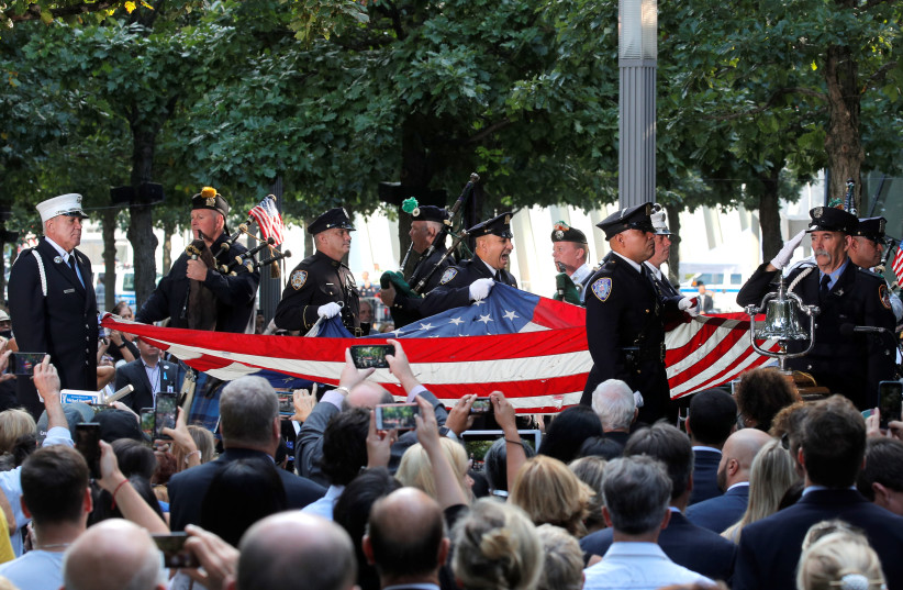 Officers cary an American flag into ceremonies commemorating the 18th anniversary of the September 11, 2001 attacks at the 911 Memorial in lower Manhattan in New York, U.S., September 11, 2019 (photo credit: REUTERS/BRENDAN MCDERMID)