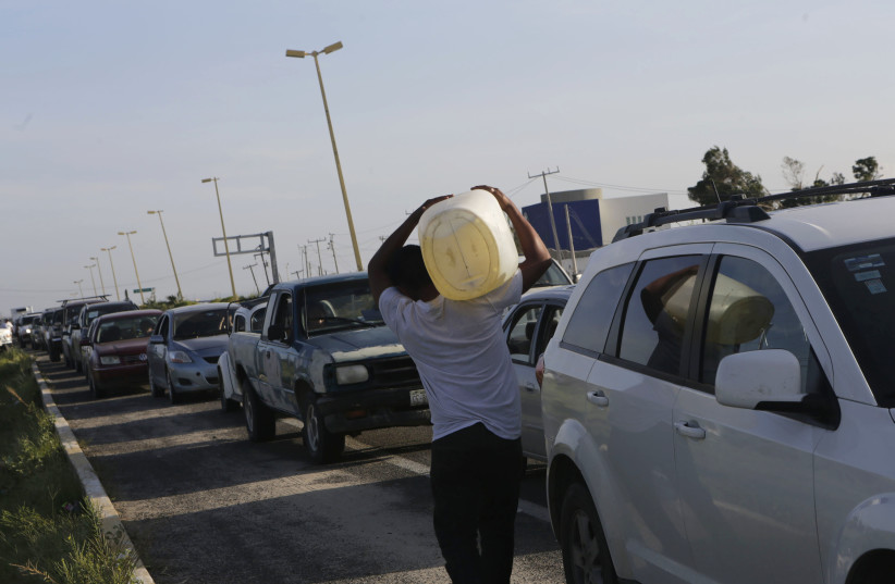A man carries a container of gas while other cars wait in line to buy gas at a Pemex gas station in San Jose del Cabo, after Hurricane Odile hit in Baja California (photo credit: REUTERS)