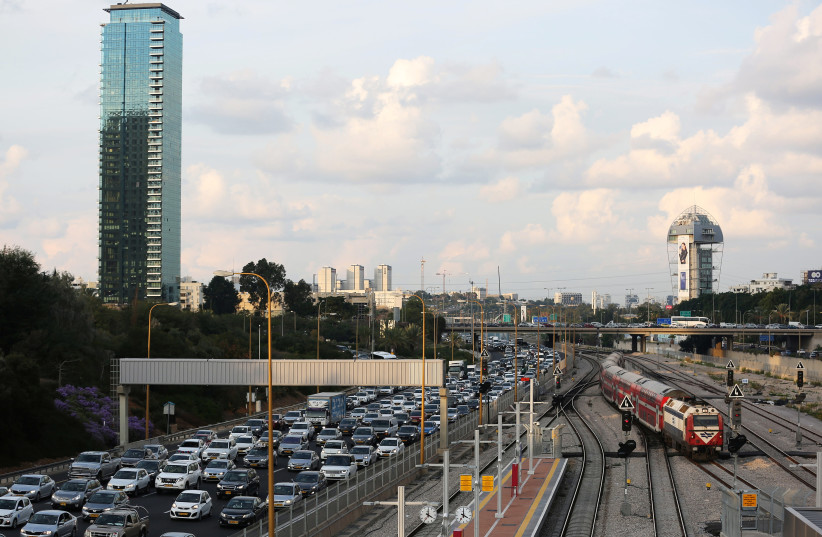 Cars drive on a highway as a train enters a station in Tel Aviv, Israel (photo credit: REUTERS)