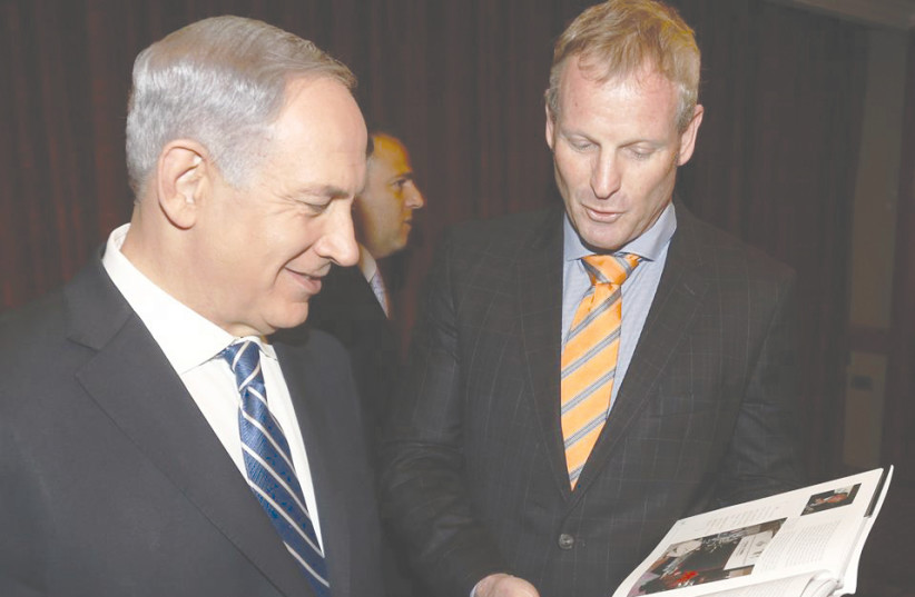 Prime Minister Benjamin Netanyahu with Hilton PR manager Motti Verses in 2013 observing a photograph from 1996, when Netanyahu was a guest of the hotel, showing his reaction to the news he was elected to serve as Prime Minister   (photo credit: HILTON HOTELS ISRAEL)