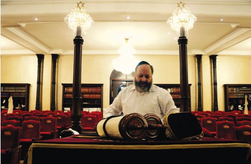 RABBI AHARON WAGNER reverently wraps the synagogue’s Torah.  (photo credit: ANNIKA HERNROTH-ROTHSTEIN)