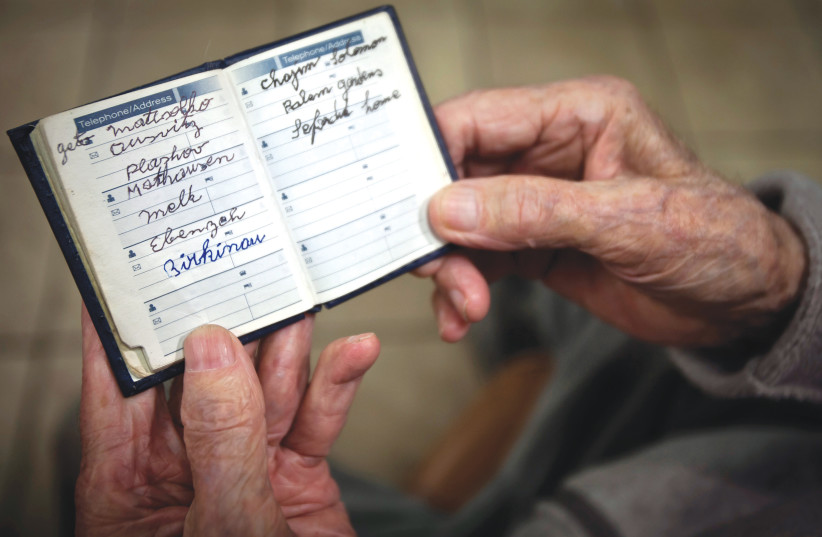 A Holocaust survivor poses with a book he carries with him everyday that documents all the different concentration camps he was held in during the Second World War, the photo was taken in New York (photo credit: REUTERS)