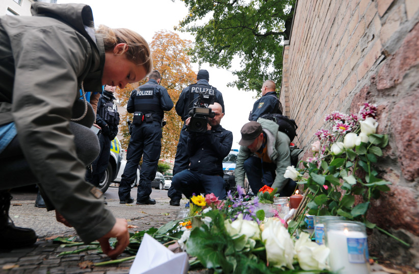 People lay flowers outside the synagogue in Halle, Germany October 10, 2019, after two people were killed in a shooting.  (photo credit: REUTERS/FABRIZIO BENSCH)