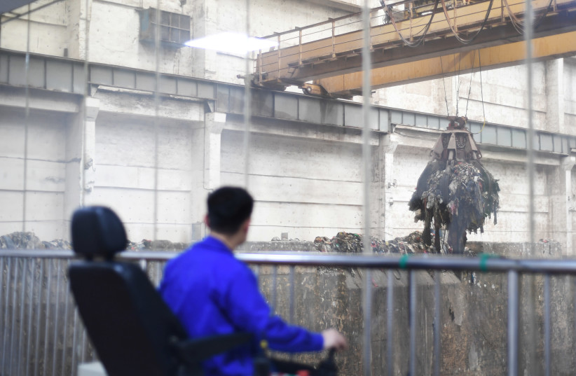 A worker operates a crane lifting garbage for incineration at a waste-to-energy plant in Kaili, Qiandongnan Miao and Dong Autonomous Prefecture, Guizhou province, China June 2, 2019. Picture taken June 2, 2019 through a glass window (photo credit: REUTERS/STRINGER)