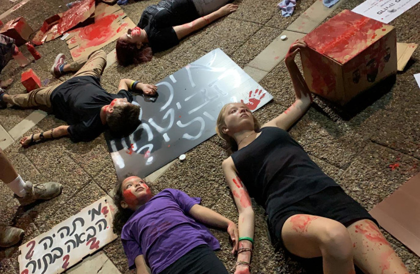 Children lie on the ground, covered in red paint, as part of a Women's Rally in Tel Aviv to protest the government's inaction on the issue of violence against women. (photo credit: Courtesy)