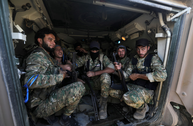 Turkey-backed Syrian rebel fighters sit inside a military vehicle near the border town of Tel Abyad, Syria, October 12, 2019 (photo credit: KHALIL ASHAWI / REUTERS)