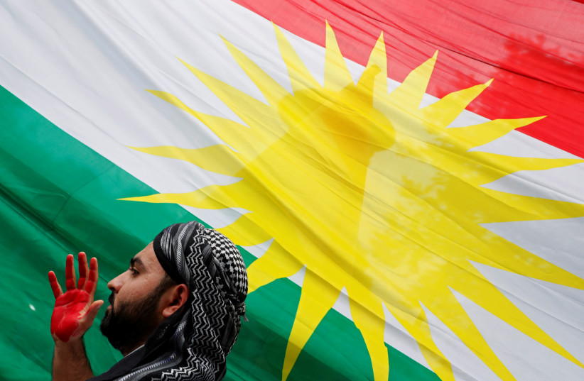 A man is seen next to Kurdistan's flag as members of The American Rojava Center for Democracy, an organization that advocates for freedom, democracy, and peace in Syria, take part with other activists in a rally to protest Turkey's incursion into Kurdish-controlled northeast Syria and urge U.S. acti (photo credit: REUTERS/CARLOS JASSO)