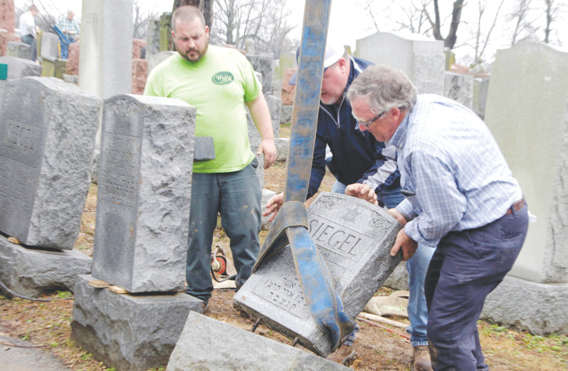 WORKERS RIGHT toppled Jewish headstones after a weekend vandalism attack on Chesed Shel Emeth Cemetery in University City, a suburb of St Louis, Missouri, in 2017 (photo credit: REUTERS/TOM GANNAM)