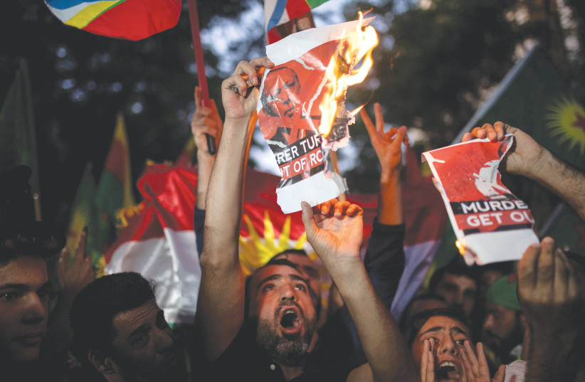 KURDS LIVING in Greece shout slogans while burning a poster depicting Turkish President Tayyip Erdogan during a demonstration against Turkey’s military action in northeastern Syria, in Athens, Friday (photo credit: ALKIS KONSTANTINIDIS / REUTERS)