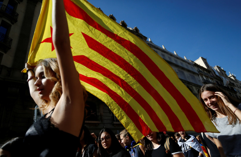 A woman waves an Estelada (Catalan separatist flag) during a protest after Spain's Supreme Court jailed nine separatist leaders, triggering violent protests in the region, in Barcelona, Spain, October 17, 2019 (photo credit: REUTERS/RAFAEL MARCHANTE)