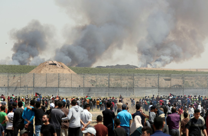 Smoke rises as Palestinians take part in a protest marking the 71st anniversary of the ‘Nakba’ (the ‘catastrophe’ that they view as resulting from the creation of Israel in 1948) at the Israel-Gaza border fence on May 15 (credit: MOHAMMED SALEM/ REUTERS)