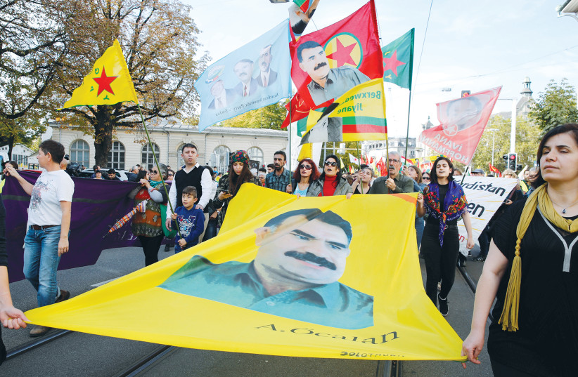 KURDISH PROTESTERS carry flags and a banner with a portrait of jailed Kurdistan Workers Party (PKK) leader Abdullah Ocalan during a demonstration against Turkey’s military action in northeastern Syria in Zurich, Switzerland, this week (photo credit: REUTERS/ARND WIEGMANN)