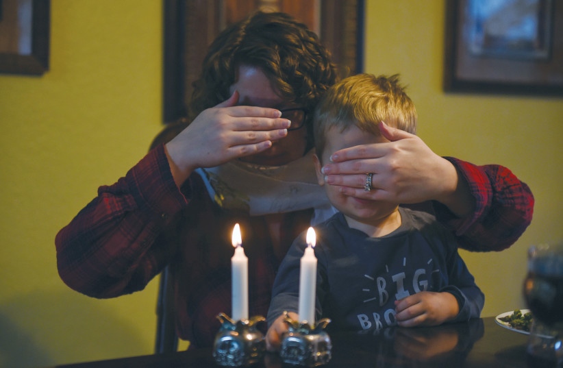 Lauren Hoffmann covers her and her son Asa’s eyes during their Shabbat dinner in San Antonio, Texas in February (photo credit: REUTERS/CALLAGHAN O’HARE)