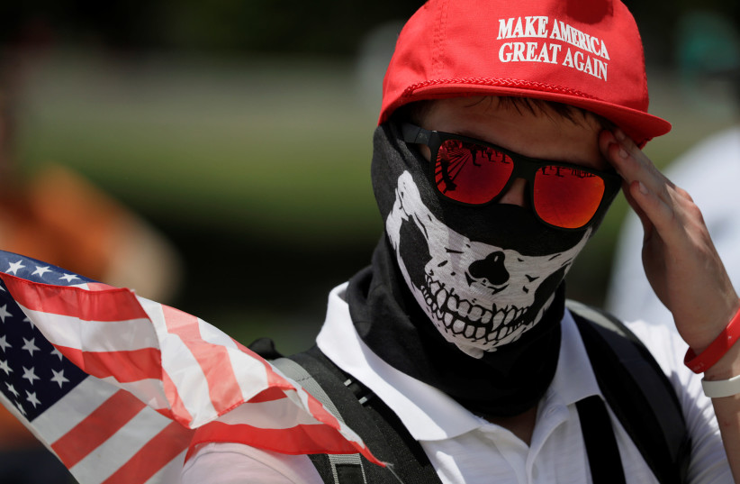 A masked demonstrator in a Donald Trump ''Make America Great Again'' hat wipes his brow as self proclaimed ''White Nationalists'', white supremacists and members of the ''Alt-Right'' gather for what they called a ''Freedom of Speech'' rally at the Lincoln Memorial in Washington, U.S. June 25, 2017 (credit: JIM BOURG / REUTERS)