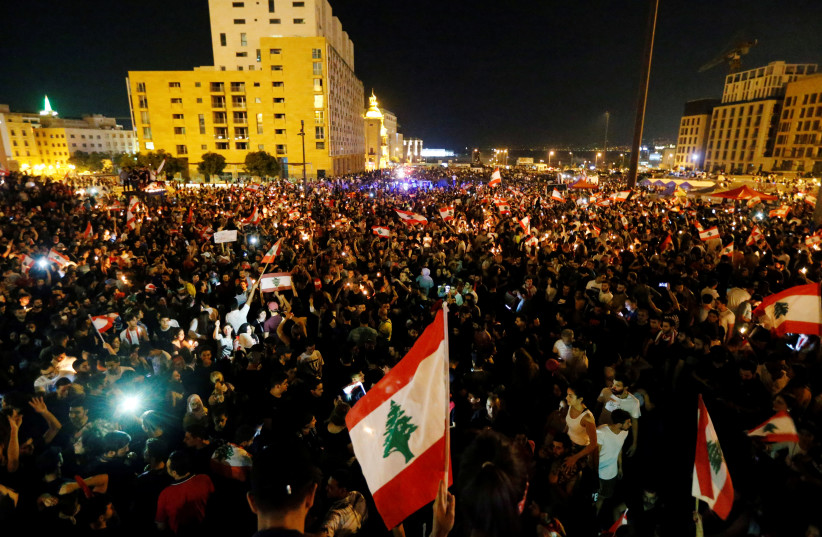 Demonstrators carry national flags during an anti-government protest in downtown Beirut, Oct. 2019 (photo credit: REUTERS/MOHAMED AZAKIR)