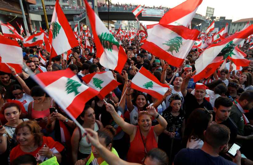 Demonstrators carry national flags and gesture during an anti-government protest along a highway in Jal el-Dib, Lebanon October 21, 2019 (photo credit: REUTERS/MOHAMED AZAKIR)
