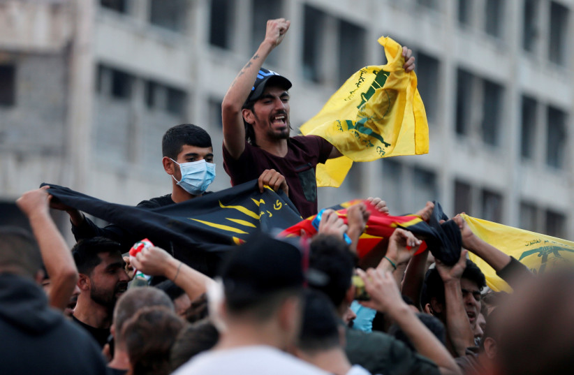 Supporters of Lebanon's Hezbollah leader Sayyed Hassan Nasrallah carry the party's flag in Beirut (photo credit: REUTERS/MOHAMED AZAKIR)