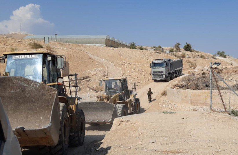 A soldier is seen walking towards construction vehicles at an illegal construction site in the West Bank (photo credit: Courtesy)