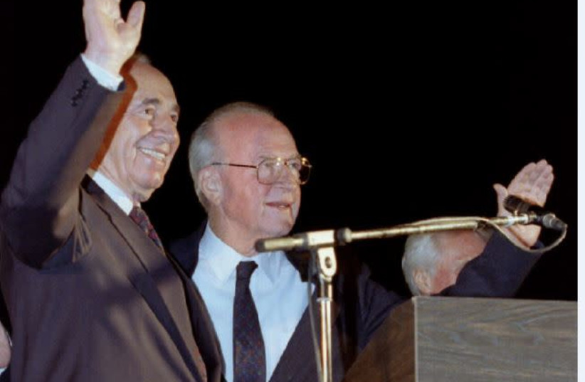 Prime Minister Yitzhak Rabin (right) and Foreign Minister Shimon Peres wave to a huge crowd at the peace rally on November 4, 1995. (photo credit: HAVAKUK LEVISON / REUTERS)
