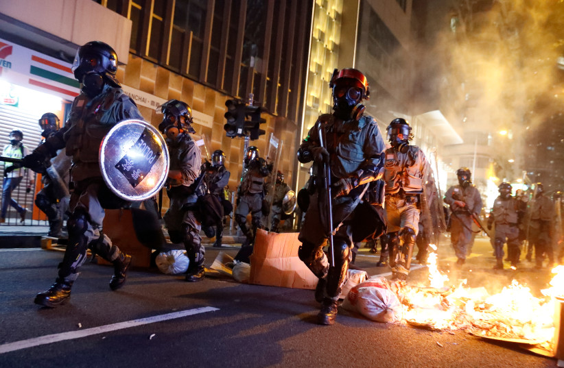 Police passes a burning barricade to break up thousands of anti-government protesters during a march billed as a global "emergency call" for autonomy, in Hong Kong, China November 2, 2019 (photo credit: REUTERS/THOMAS PETER)