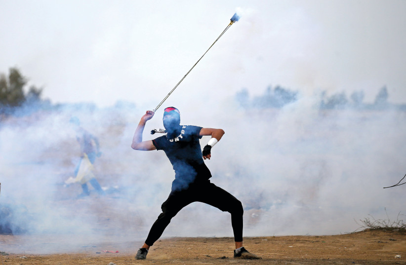 A PALESTINIAN slings a stone at Israeli soldiers (photo credit: REUTERS)
