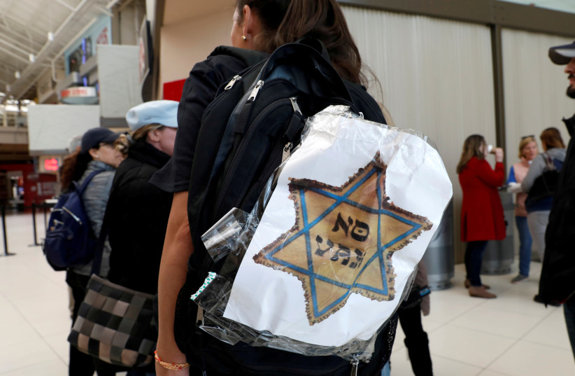 A woman opposed to childhood vaccinations wears a "No Vax" sign on her backpack as she takes part in a demonstration after officials in Rockland County, a New York City suburb, banned children not vaccinated against measles from public spaces, in West Nyack, New York, U.S. March 28, 2019. (photo credit: REUTERS)