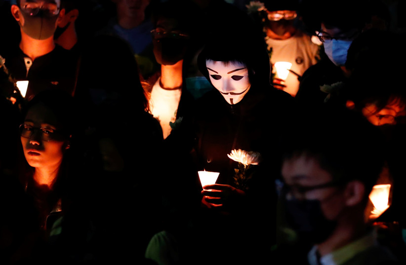 A man wears a Guy Fawkes mask during a ceremony to pay tribute to Chow Tsz-lok, 22, a university student who fell during protests at the weekend and died early on Friday morning, at the Hong Kong University of Science and Technology, in Hong Kong, China November 8, 2019 (photo credit: TYRONE SIU/ REUTERS)