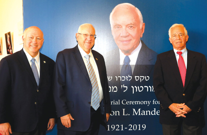 PRESIDENT REUVEN RIVLIN is flanked by Stephen Hoffman (left), chairman of the board of the Mandel Foundation, and Prof. Jehuda Reinharz, president and CEO of the Mandel Foundation, against a backdrop featuring a larger-than-life image of Mort Mandel. (photo credit: SIVAN FARAG)