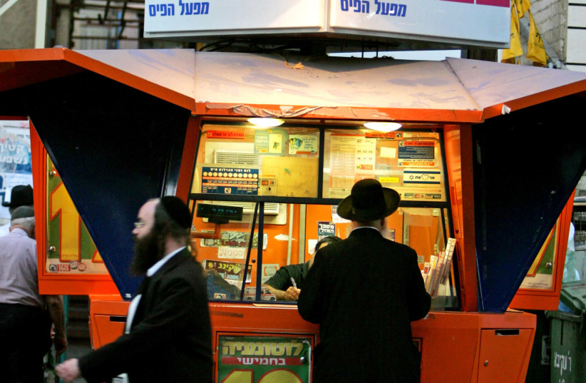 An Ultra orthodox Jewish man stands in front of a lottery station in Bnei Brak city, near Tel Aviv, September 28, 2005. (credit: GIL COHEN MAGEN)