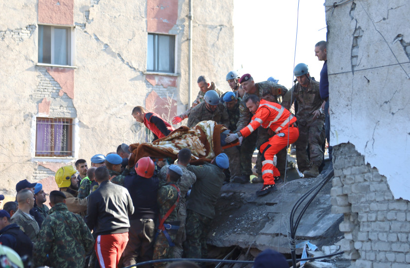 Military and emergency personnel carry an injured man on a stretcher near a damaged building in Thumane, after an earthquake shook Albania, November 26, 2019 (photo credit: REUTERS/FLATOS BYTYCI)