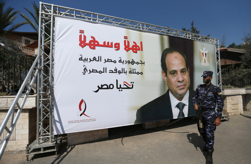 A Palestinian member of Hamas security forces stands guards next to a poster depicting Egypt's President Abdel Fattah al-Sisi, outside the Palestinian cabinet headquarters in Gaza City, October 3, 2017 (photo credit: REUTERS/IBRAHEEM ABU MUSTAFA)