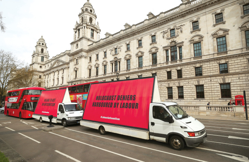 VANS WITH slogans aimed at the Labour Party are driven around Parliament Square in London ahead of a debate on antisemitism last year.  (photo credit: HANNAH MCKAY/ REUTERS)