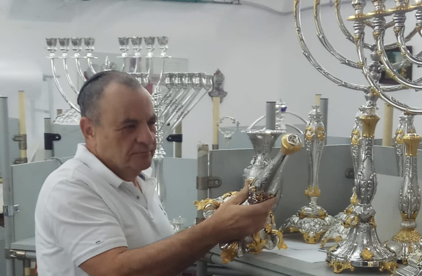 CEO of Hazorfim Yakov Merdinger looks at produced silver candlesticks and menorahs.  (photo credit: HAZORFIM)