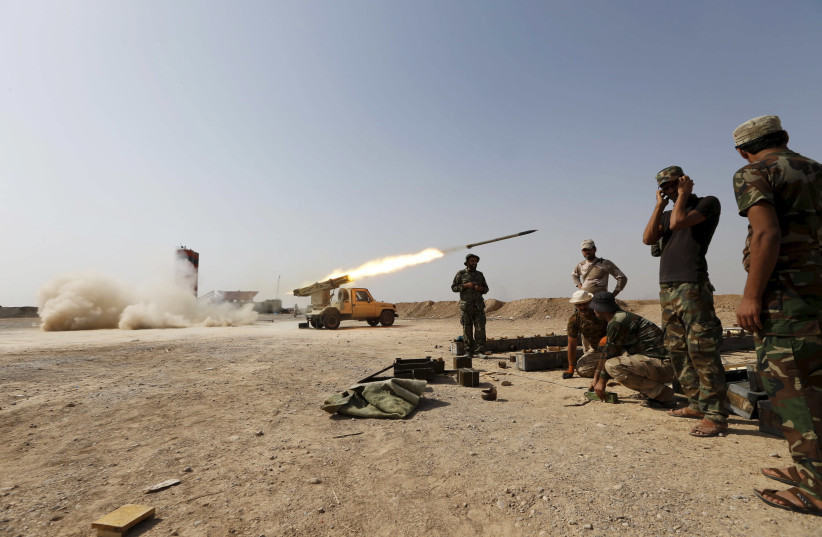 Shi'ite fighters fire a rocket toward Islamic State militants in Baiji, north of Baghdad, 2015 (credit: THAIER AL-SUDANI/REUTERS)