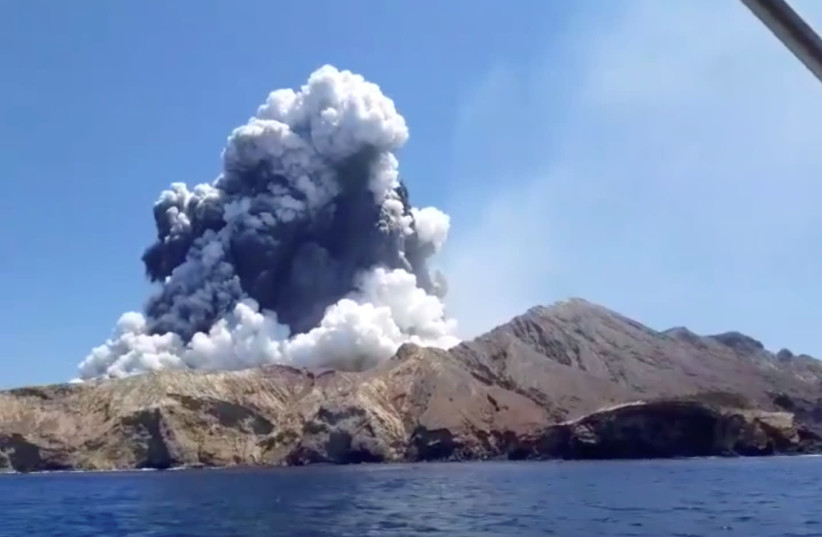 Smoke from the volcanic eruption of Whakaari, also known as White Island, is pictured from a boat (photo credit: REUTERS)