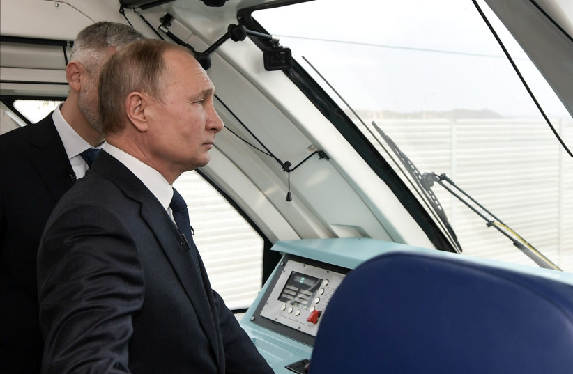Russian President Vladimir Putin stands in a cabin of a train traveling from Kerch to Taman across a bridge, which was constructed to connect the Russian mainland with the Crimean Peninsula across the Kerch Strait, in Kerch, Crimea December 23, 2019 (photo credit: SPUTNIK/ALEXEI NIKOLSKY/KREMLIN VIA REUTERS)