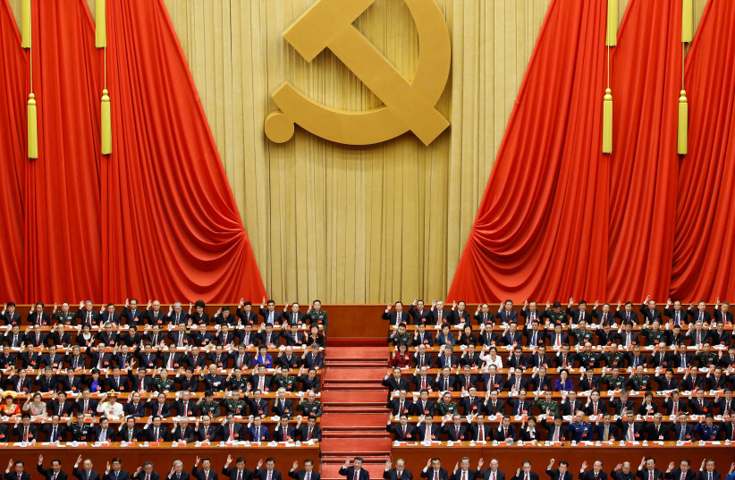 Chinese President Xi Jinping (front row, center) and fellow delegates raise their hands as they take a vote at the closing session of the 19th National Congress of the Communist Party of China, in Beijing, China October 24, 2017 (photo credit: THOMAS PETER/REUTERS)