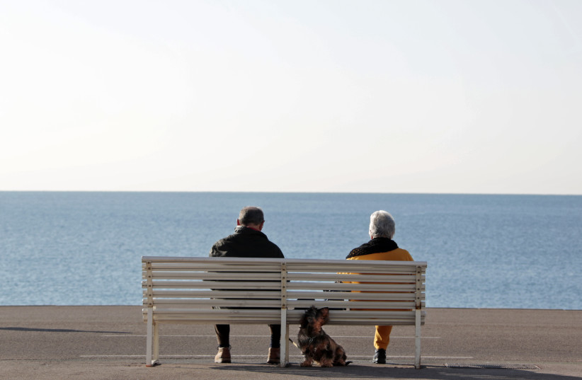 Elderly people sit on a bench to take in the sun along the Promenade Des Anglais in Nice (credit: ERIC GAILLARD/REUTERS)