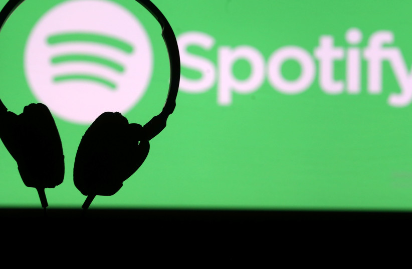 A headset is seen in front of a screen projection of Spotify logo, in this picture illustration (photo credit: REUTERS)