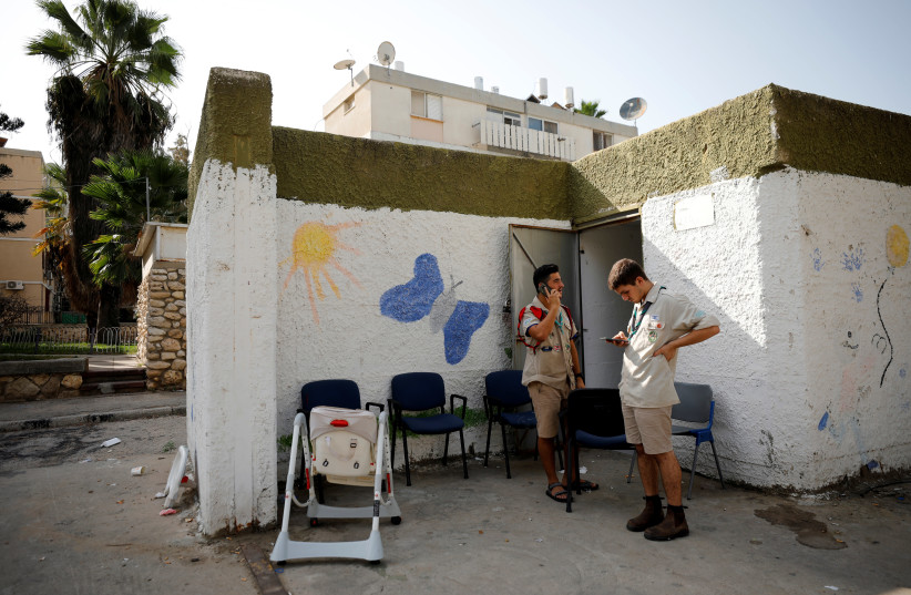 Scouts use their mobile phones while standing near a bomb shelter as a spike in cross-border violence with Gaza continues, in Ashkelon (photo credit: AMIR COHEN/REUTERS)